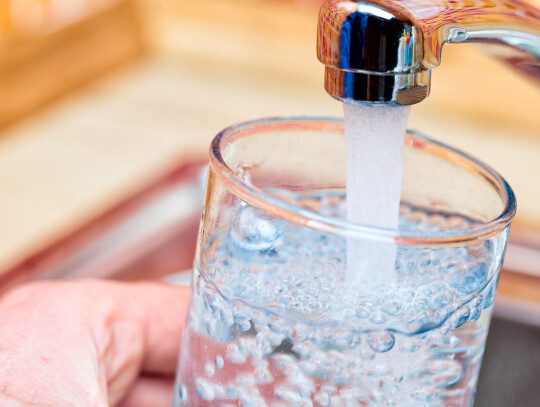 Filling up a glass with drinking water from kitchen tap