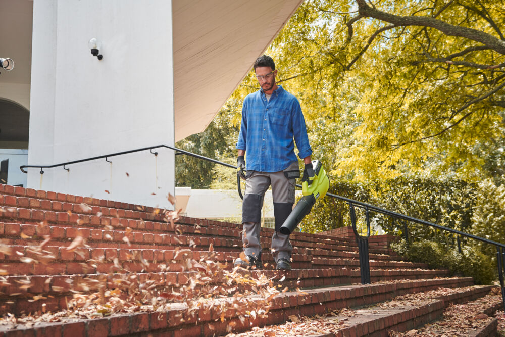Mężczyzna sprząta mokre liście ze schodów z użyciem dmuchawy do liści RYOBI